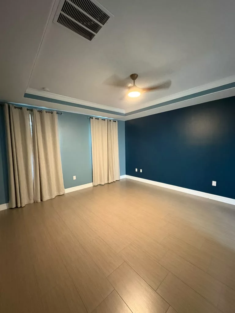 Freshly painted room with deep blue and soft teal walls, white trim and warm wood flooring
