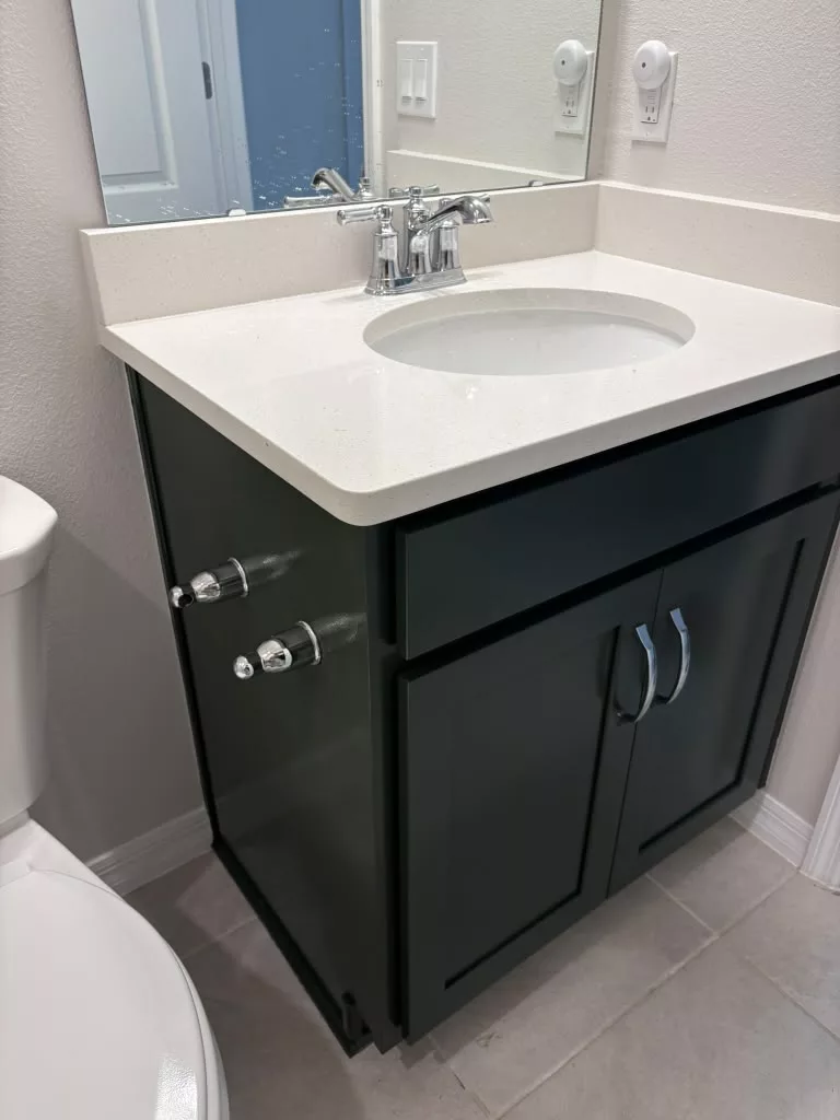 Dark refinished bathroom vanity with silver handles and white sink