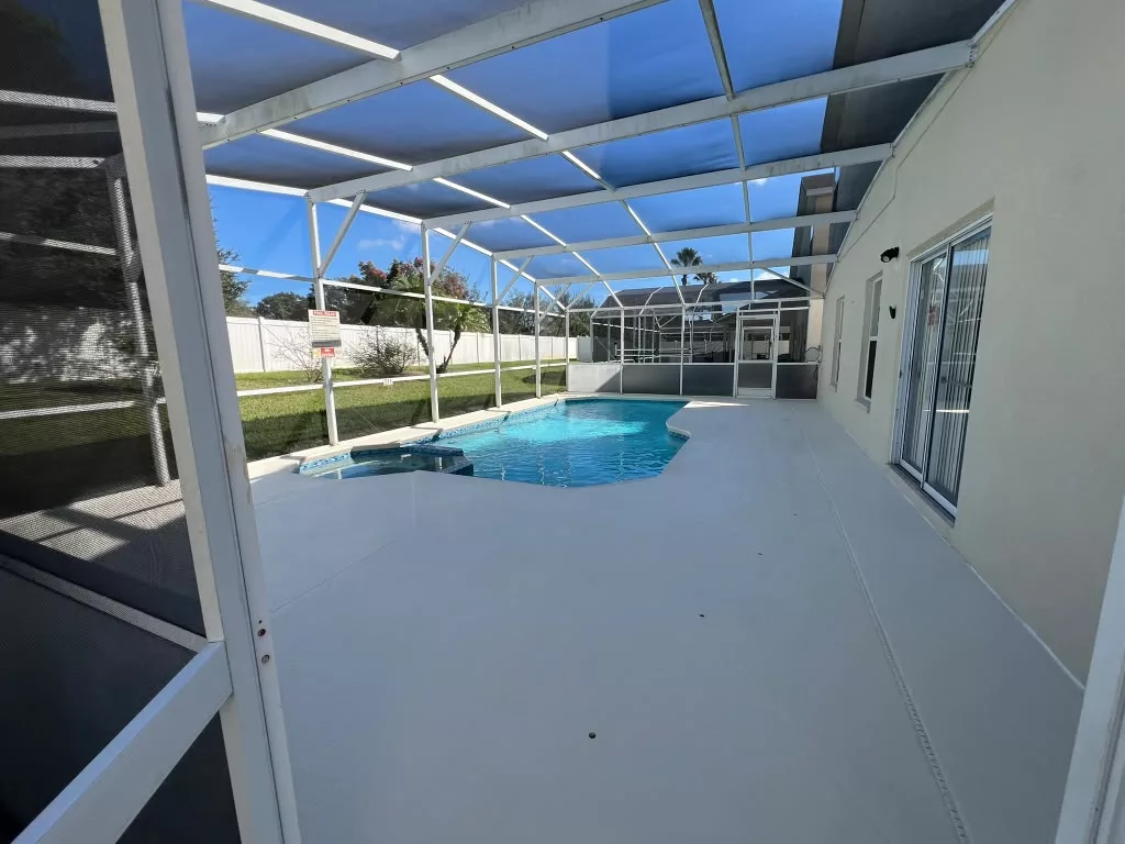 Light refinished poolside patio beneath a screened enclosure